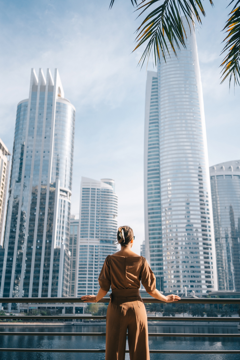 Woman overlooking Dubai Marina skyscrapers and waterfront, representing high net-worth expatriates planning wealth with Indexed Universal Life Insurance in Dubai